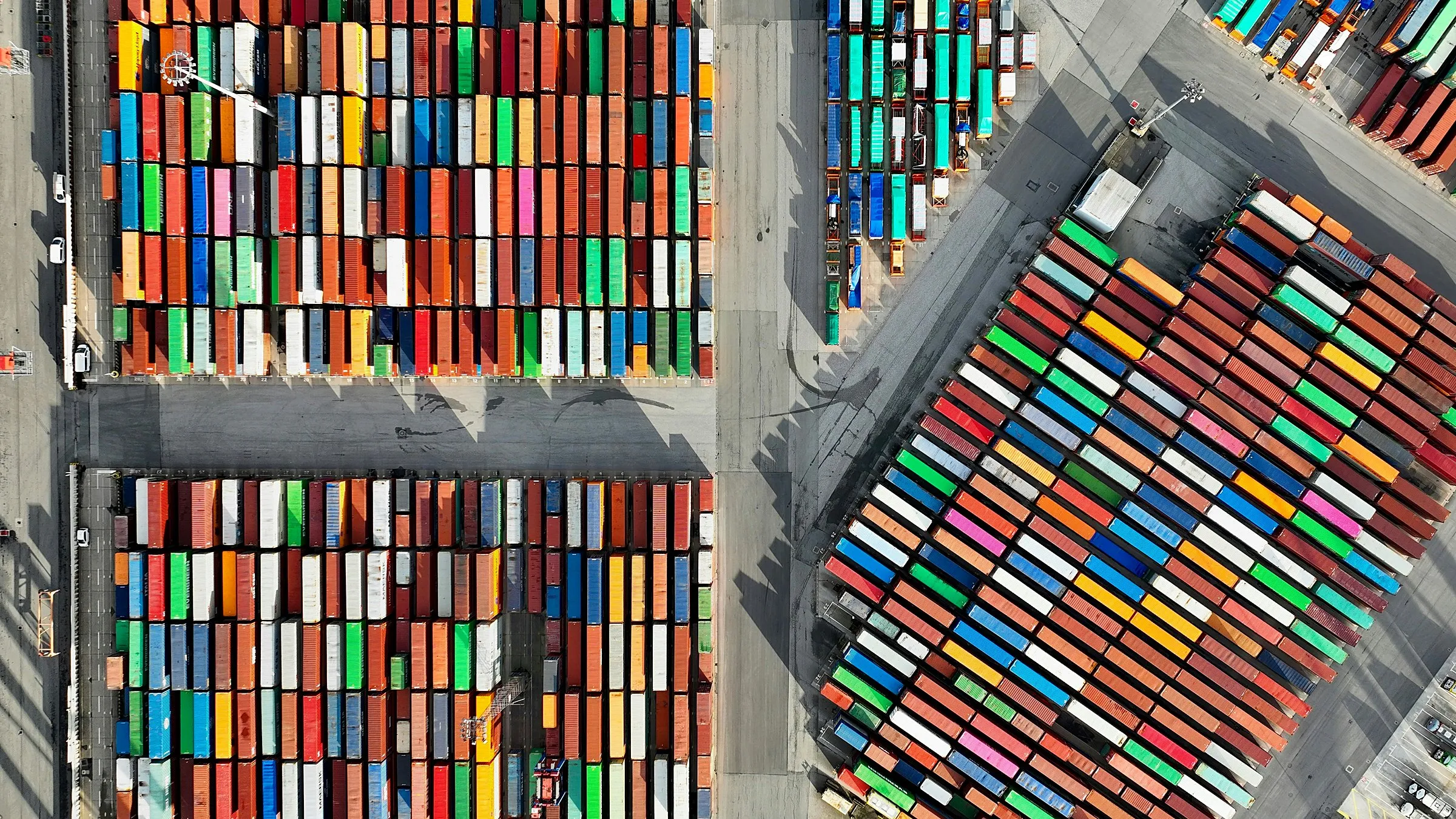 An aerial view of colourful shipping containers stacked in rows at a port