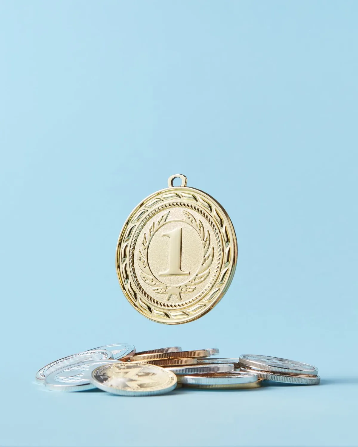 A gold medal floating above a small pile of coins